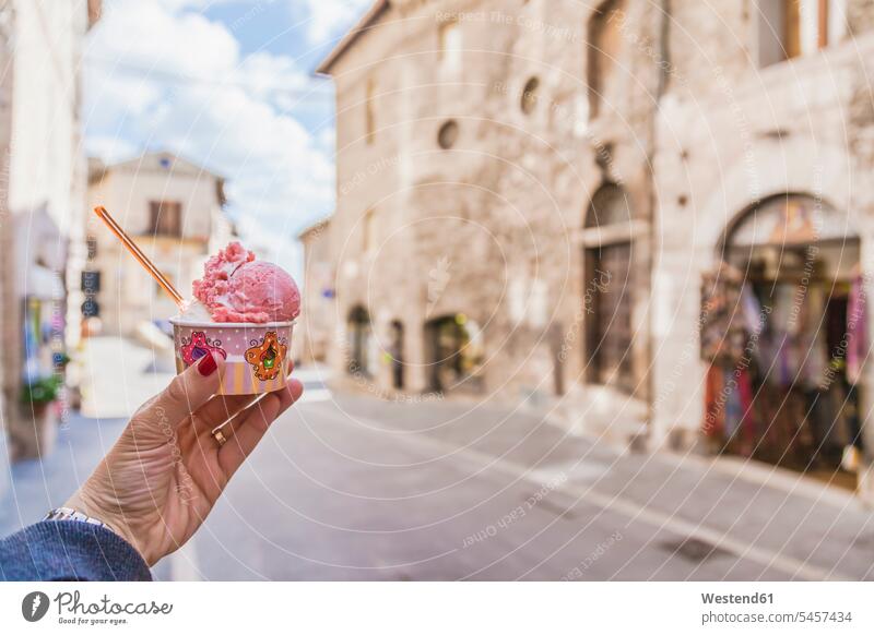 Italy, Umbria, Assisi, woman's hand holding a traditional Italian gelato in the town center sundae icecream sundaes cup focus on foreground