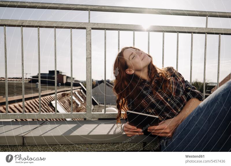 Redheaded woman with tablet relaxing on rooftop terrace business life business world business person businesspeople business woman business women businesswomen