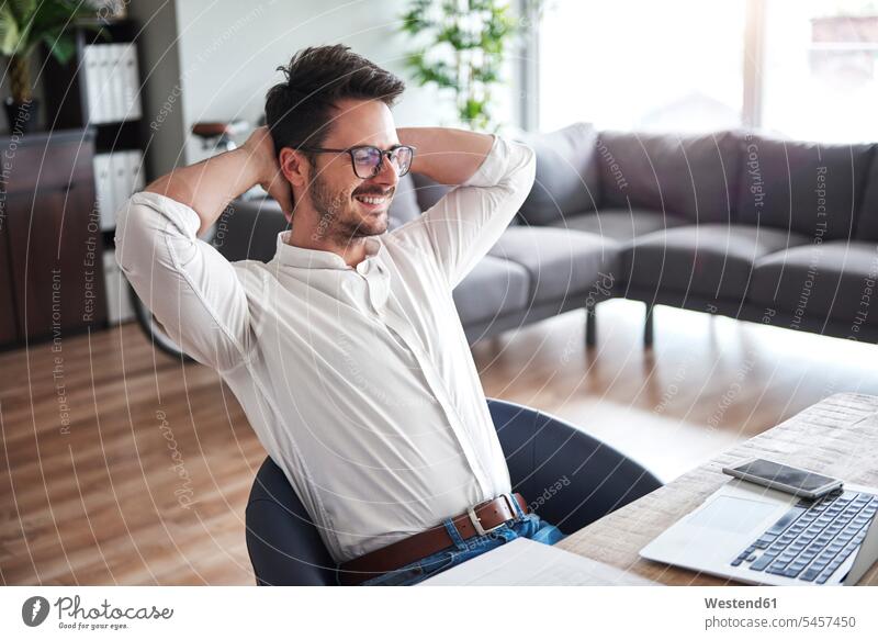Content businessman sitting at desk at home office Seated desks Businessman Business man Businessmen Business men content pleased Table Tables business people