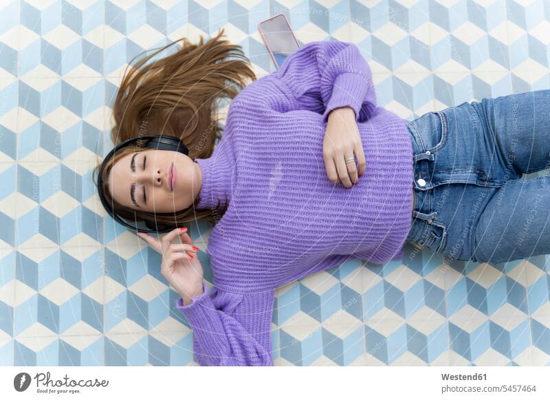 Portrait of young woman with eyes closed lying on the floor listening music with headphones human human being human beings humans person persons