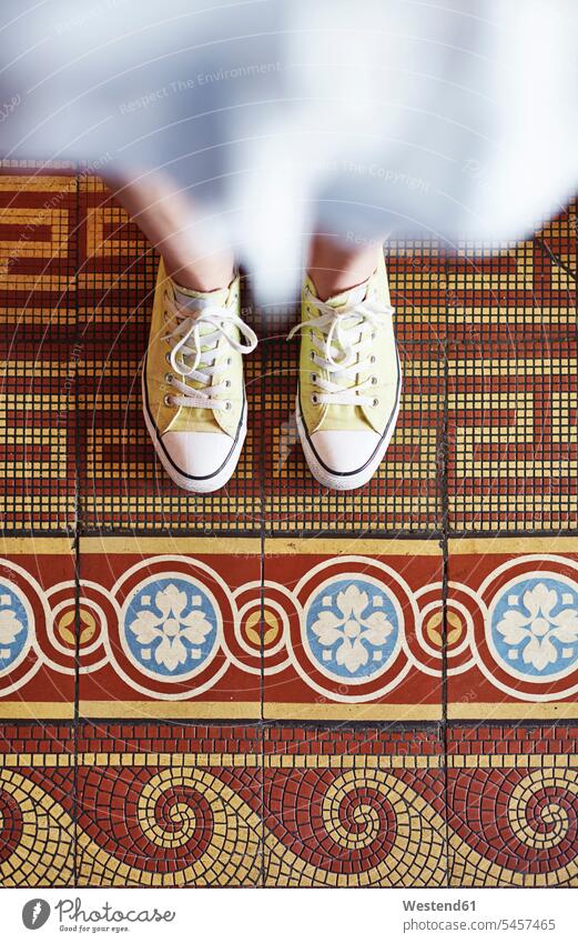 Woman wearing yellow sneakers standing on mosaic floor, partial view Sneakers woman females women mosaic flooring colour colours Adults grown-ups grownups adult