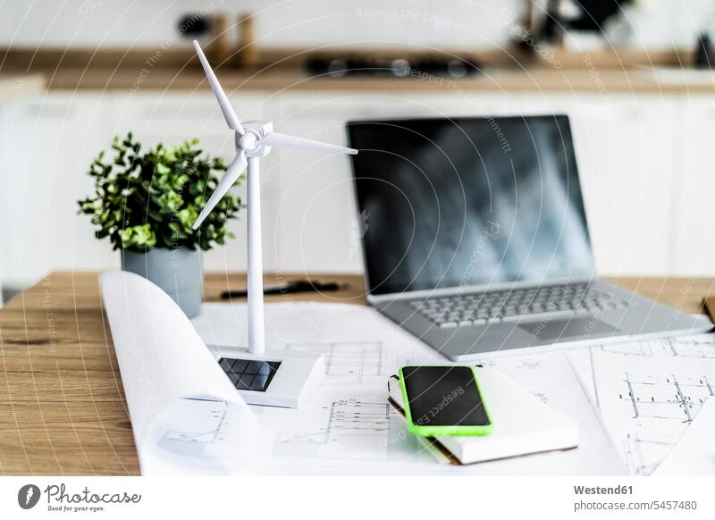 Wind turbine model, construction plan, cell phone and laptop on table in office accessible ecology environment and nature protection Environment Conservation