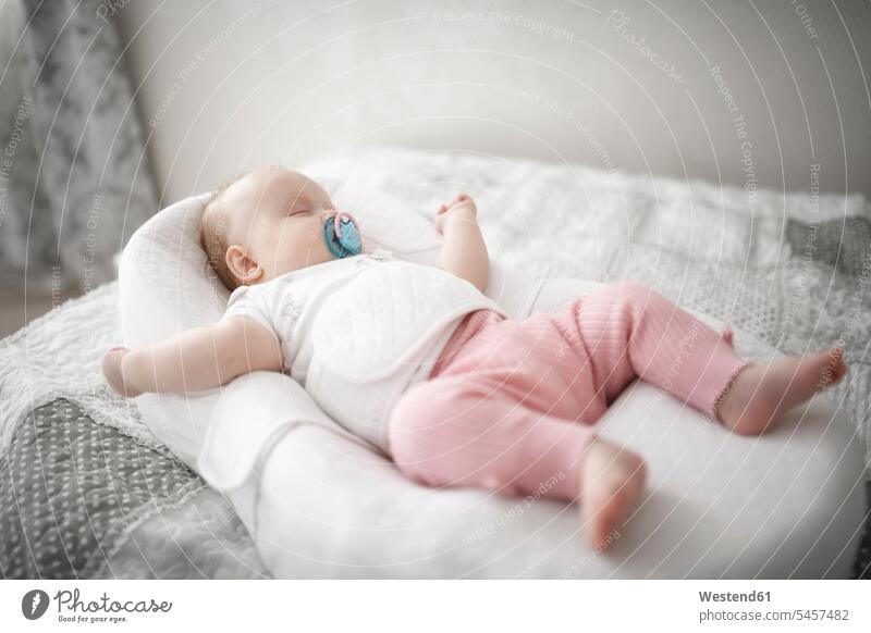 Cute baby girl sleeping on the bed cushions comforter Pacifiers soother relax relaxing asleep peaceable peaceful Contented Emotion pleased laying down lie