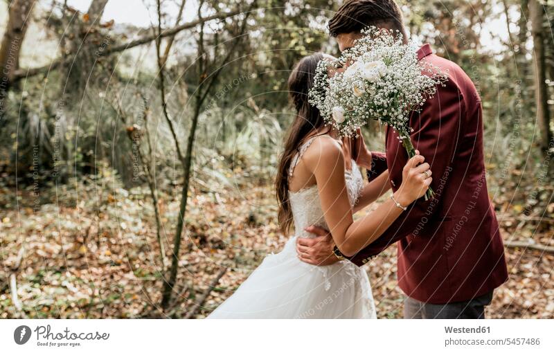 Unrecognizable bride and groom kissing in forest behind bouquet of flowers Wedding getting married marrying Marriage kisses brides Bunch of Flowers Bouquet