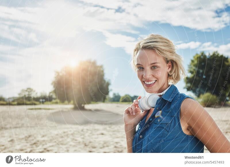 Portrait of happy young woman with headphones on the beach headset beaches females women portrait portraits happiness Adults grown-ups grownups adult people