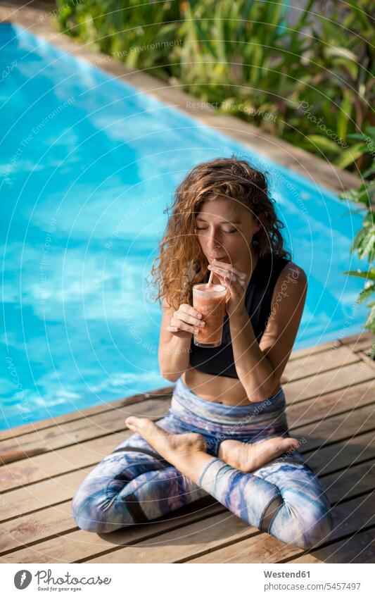 Woman practicing yoga at poolside, drinking juice, Costa Rica front front views frontal Frontal View head on head-on View From Front Drinking Glass