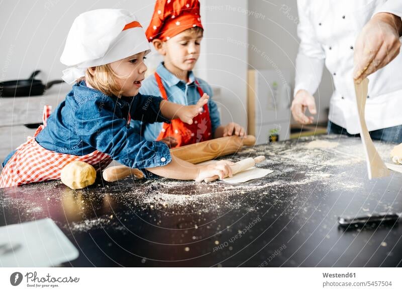 Father with two kids preparing dough for homemade gluten free pasta in kitchen at home Chefs cook cooks hold learn smile delight enjoyment Pleasant pleasure