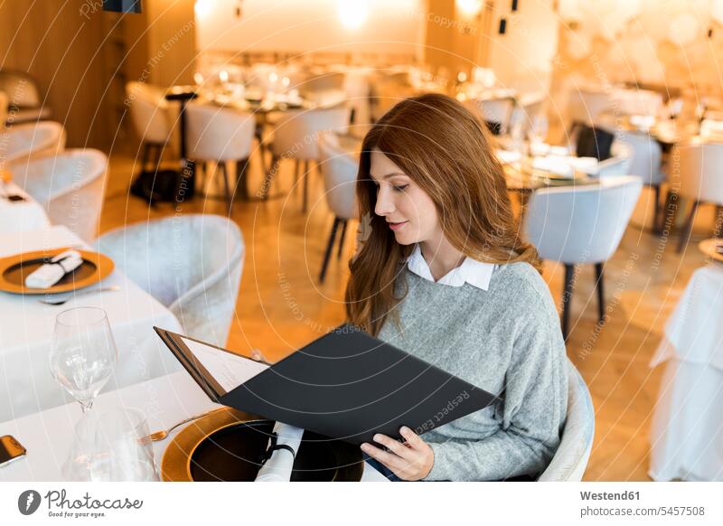 Woman sitting at table in a restaurant reading menu restaurants woman females women Seated Table Tables Menus menues Adults grown-ups grownups adult people