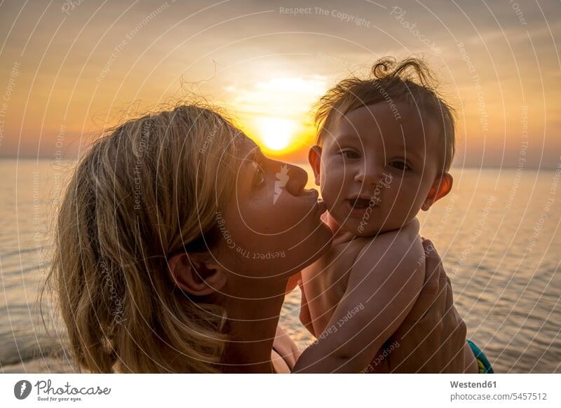 Vietnam, Phu Quoc island, Ong Lang beach, Mother kissing baby in beach at sunset outdoors location shots outdoor shot outdoor shots sunsets sundown atmosphere