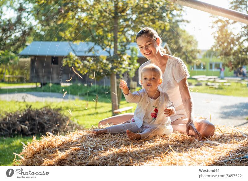 Happy mother and little daughter playing with straw on a farm mommy mothers ma mummy mama Straw daughters happiness happy parents family families people persons