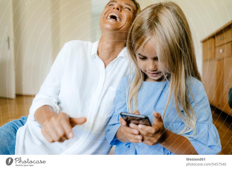 Laughing mother and daughter looking at smartphone daughters eyeing Smartphone iPhone Smartphones laughing Laughter mommy mothers mummy mama home at home child