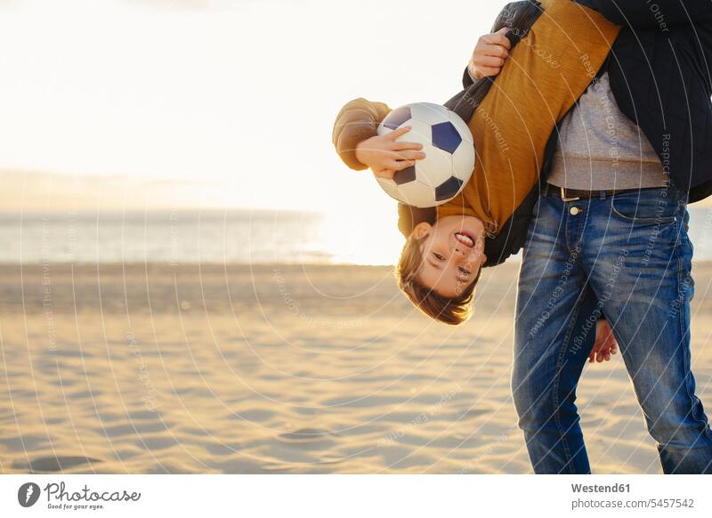 Father holding son with football upside down on the beach at sunset sons manchild manchildren sunsets sundown soccer ball soccer balls footballs beaches father