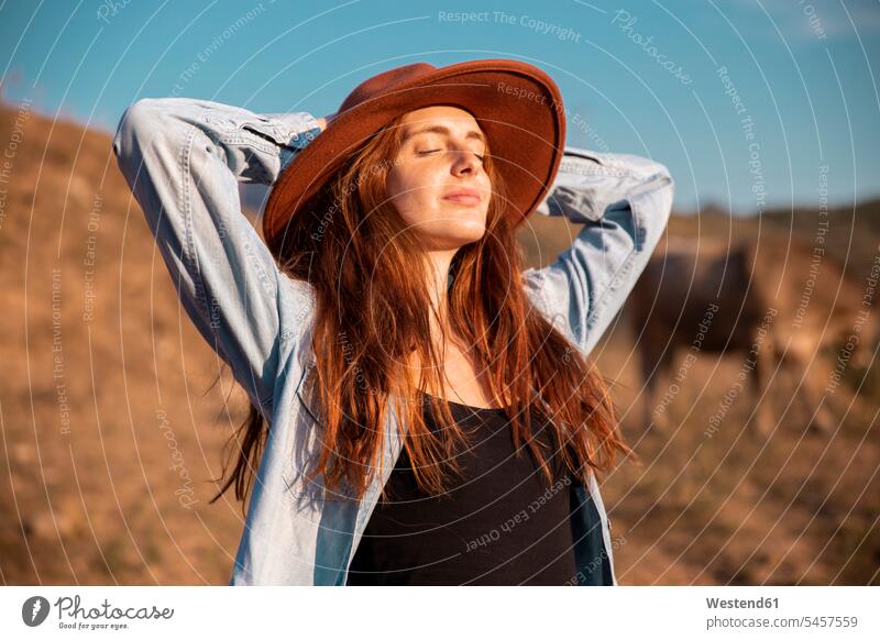 Young woman wearing a hat relaxing and enjoying the rural landscape females women indulgence enjoyment savoring indulging relaxed relaxation landscapes scenery