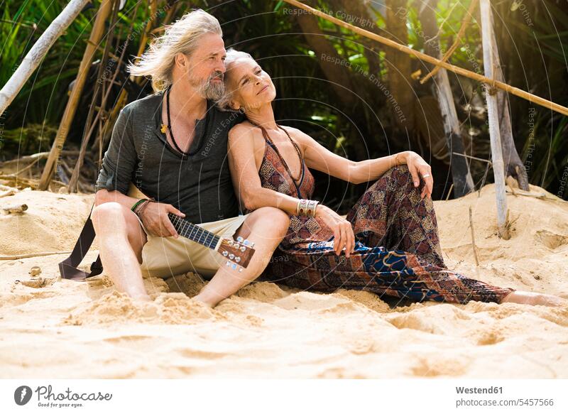 Portrait of happy senior hippie couple with guitar relaxing on the beach relaxation beaches senior couple elder couples senior couples happiness guitars