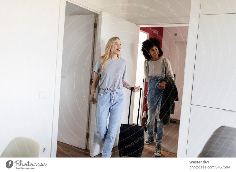 Two happy women with baggage arriving in accomodation accommodation quarters Lodging luggage girlfriend Girlfriends girl friend girl friends arrival woman