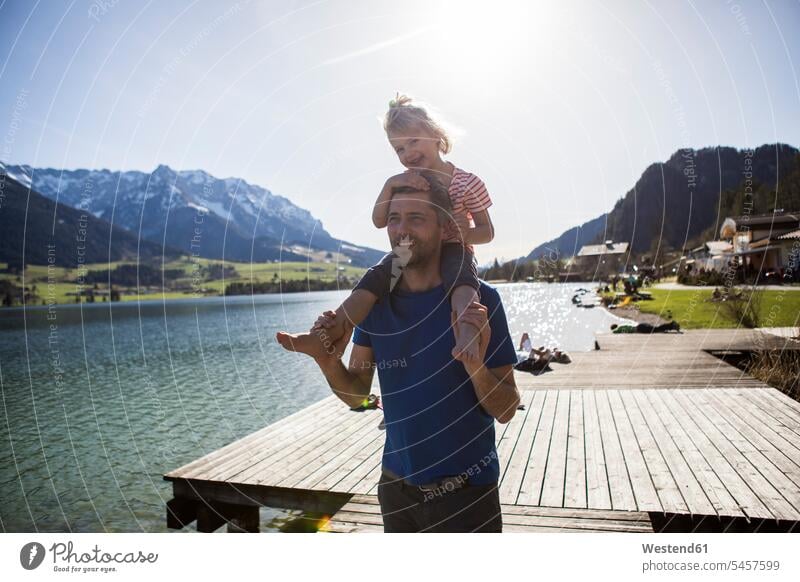 Austria, Tyrol, Walchsee, happy father carrying daughter on shoulders at the lake family families lakes happiness Lakeshore Lake Shore lakeside pa fathers daddy