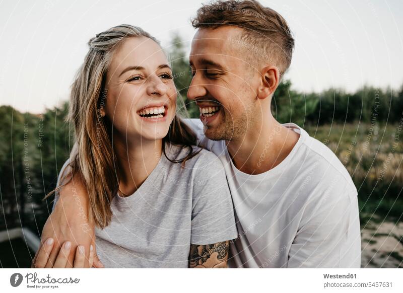 Portrait of young laughing couple T- Shirt t-shirts tee-shirt embrace Embracement hug hugging in the evening delight enjoyment Pleasant pleasure Cheerfulness