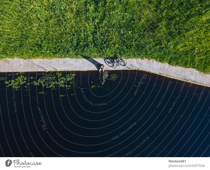 Drone shot of mid adult man with bicycle sitting at river coast color image colour image leisure activity leisure activities free time leisure time outdoors