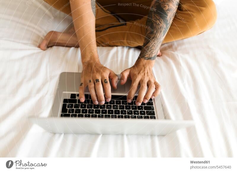 Close-up of tattooed man using laptop in bed beds Laptop Computers laptops notebook sitting Seated men males tattoos computer computers Adults grown-ups