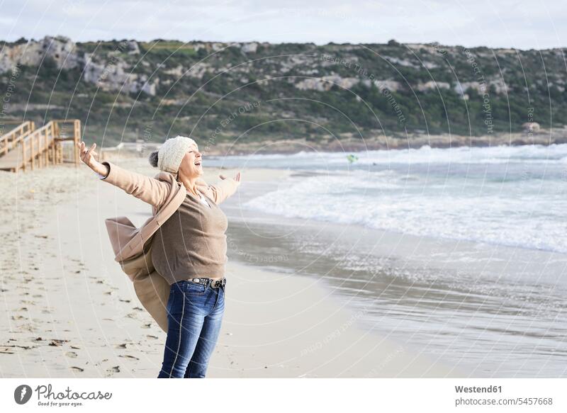 Spain, Menorca, happy senior man standing at seashore in winter senior women elder women elder woman old senior woman hibernal seafront Oceanside Sea Shore