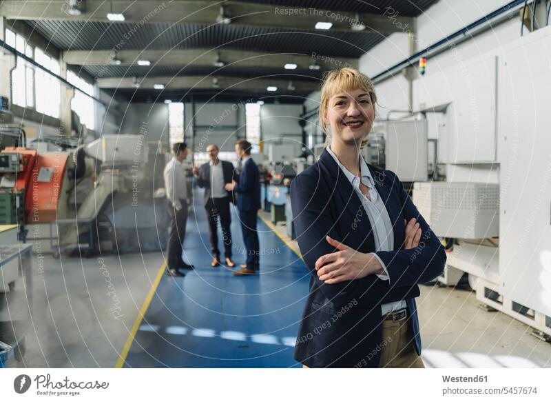 Portrait of a confident businesswoman in a factory with colleagues in backgound Occupation Work job jobs profession professional occupation business life