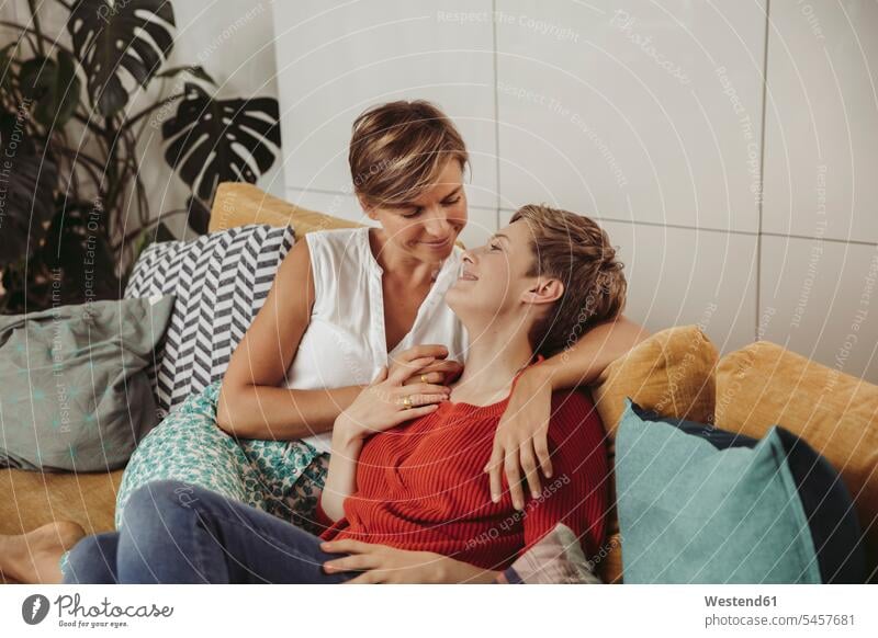 Happy lesbian couple cuddling on couch happiness happy twosomes partnership couples snuggle cuddle snuggling settee sofa sofas couches settees people persons