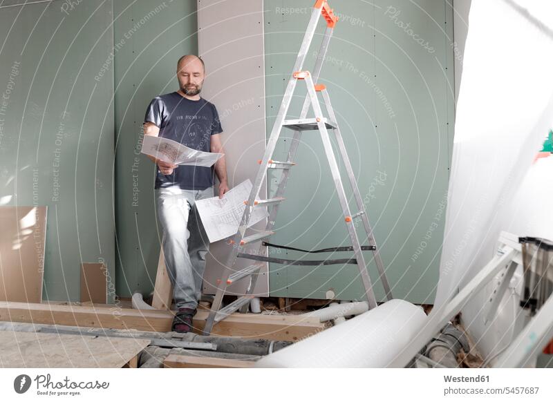 Man on construction site at home studying plan human human being human beings humans person persons bald head baldy Completely Bald maps architectural drawing