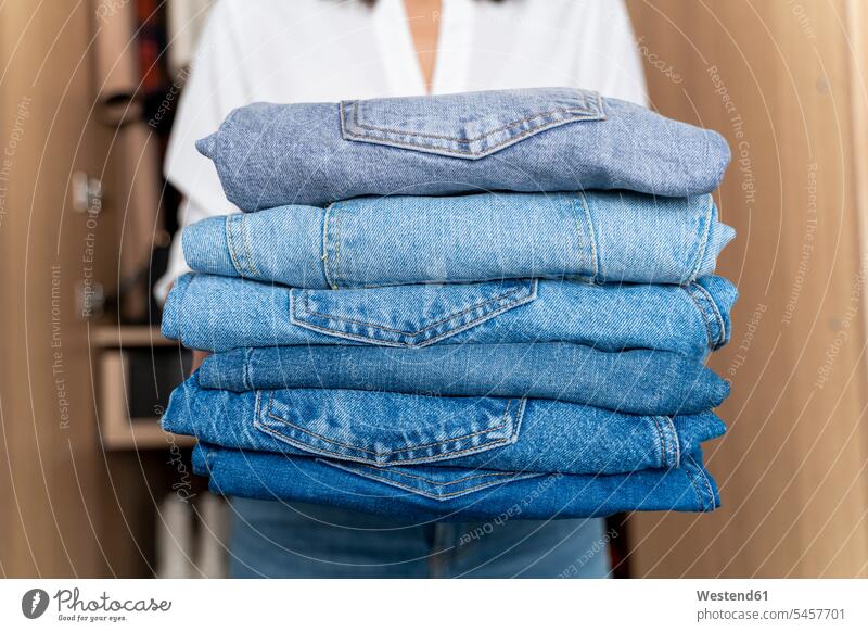 Woman holding stack of blue jeans pants Trouser Denim Jeans colour colours at home free time leisure time neat Orderliness Arrangements Positioning Positionings