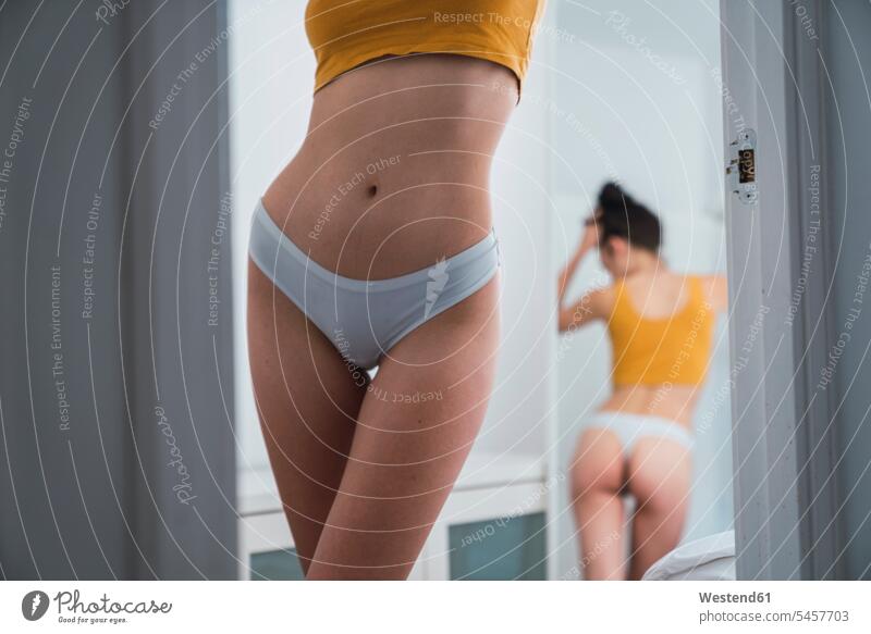 Young woman in underwear at home reflected in mirror - a Royalty