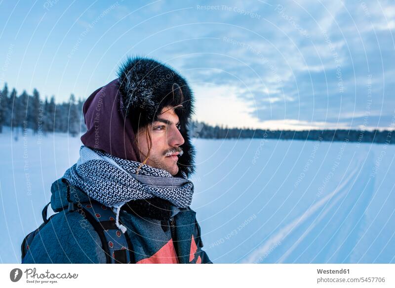 Portrait of man in winter landscape with frozen moustache, Ounasjaervi, Enontekioe, Finland touristic tourists Cap - Hat caps hat hats scarfs scarves seasons