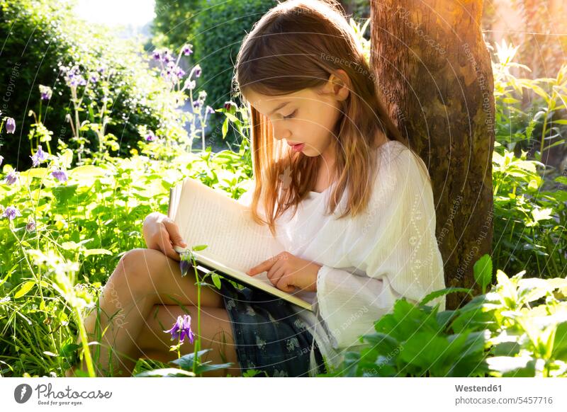 Little girl leaning against tree trunk reading a book human human being human beings humans person persons caucasian appearance caucasian ethnicity european 1