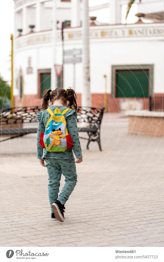 Rear view of girl walking with backpack and mask on square human human being human beings humans person persons children kid kids back-pack back-packs backpacks