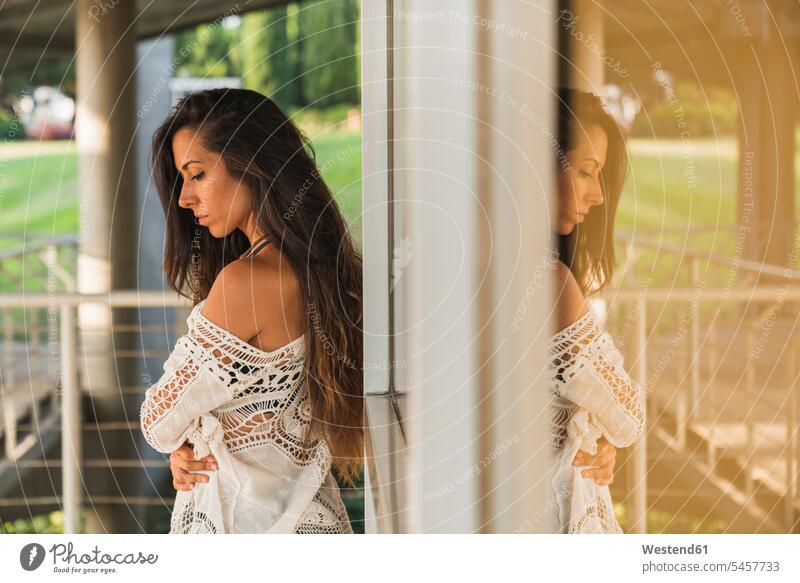 Serious brunette young woman at a window outdoors windows females women serious earnest Seriousness austere Adults grown-ups grownups adult people persons