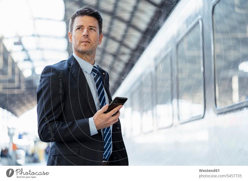 Businessman with cell phone on station platform train station mobile phone mobiles mobile phones Cellphone cell phones Railroad Platform Business man