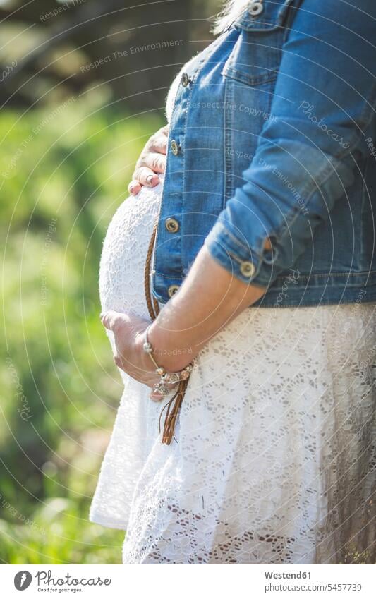 Pregnant woman holding her belly, close up dress dresses denim jacket jeans jackets unrecognisable person Unrecognizable People Unrecognizable Person
