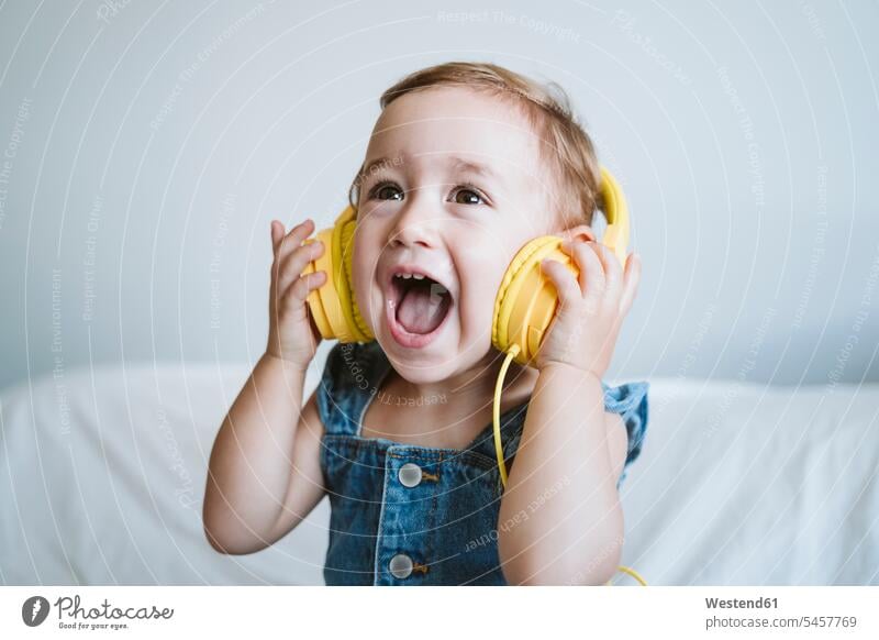 Baby girl at home listening to music on bed Bed - Furniture beds headphone headset hear Seated sit delight enjoyment Pleasant pleasure Cheerfulness exhilaration