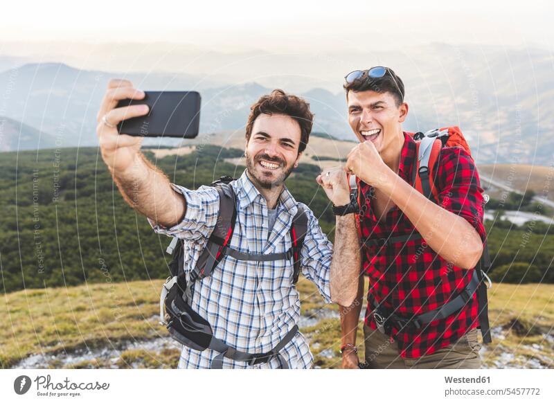 Italy, Monte Nerone, two happy hikers on top of a mountain taking a selfie man men males Selfie Selfies hiking summit mountaintops summits mountain top