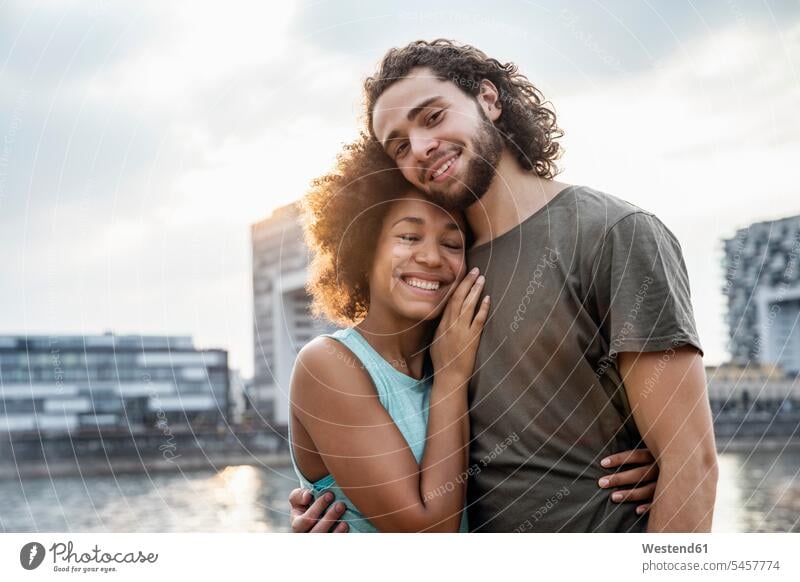Germany, Cologne, portrait of happy couple at the riverside happiness portraits riverbank relaxed relaxation twosomes partnership couples sunset sunsets sundown