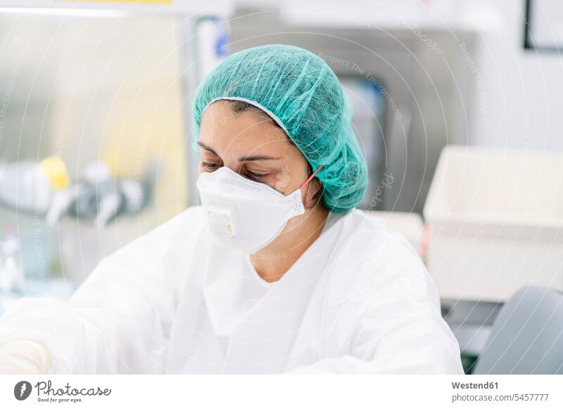 Close-up of female pharmacist wearing surgical mask and cap while working in laboratory color image colour image Spain indoors indoor shot indoor shots interior