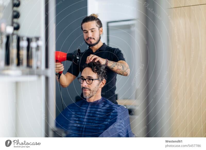 Hairdresser blow drying man's hair at salon color image colour image indoors indoor shot indoor shots interior interior view Interiors day daylight shot