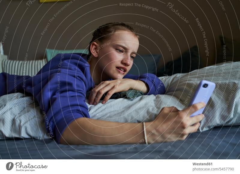 Portrait of girl lying on bed at home using smartphone for video chat Bed - Furniture beds telecommunication phones telephone telephones cell phone cell phones
