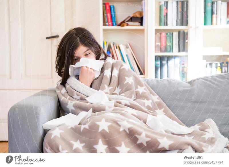 Sick girl sitting on the couch at home blowing nose females girls ill sick Seated settee sofa sofas couches settees child children kid kids people persons