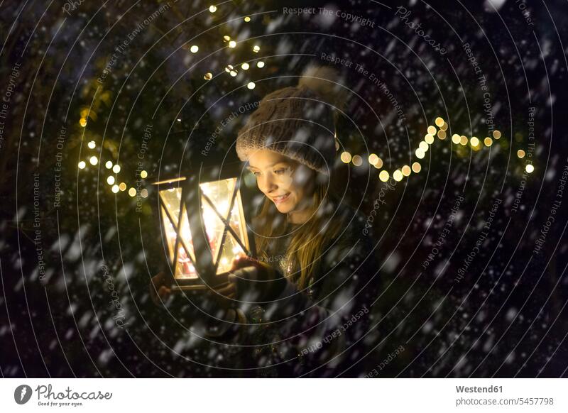 Happy girl with lighted lantern by night at snowfall females girls portrait portraits lanterns illuminated lit Illuminating at night nite night photography