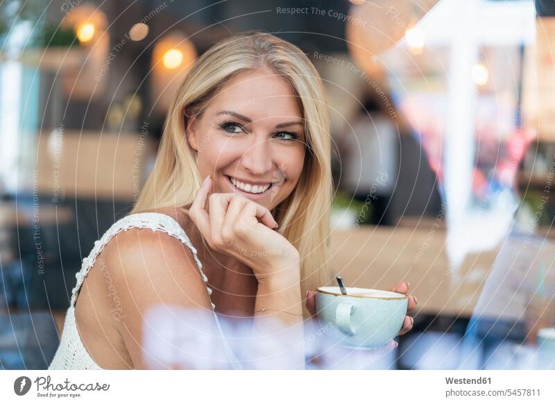 Portrait of smiling blond woman drinking coffee in a cafe human human being human beings humans person persons celibate celibates singles solitary people