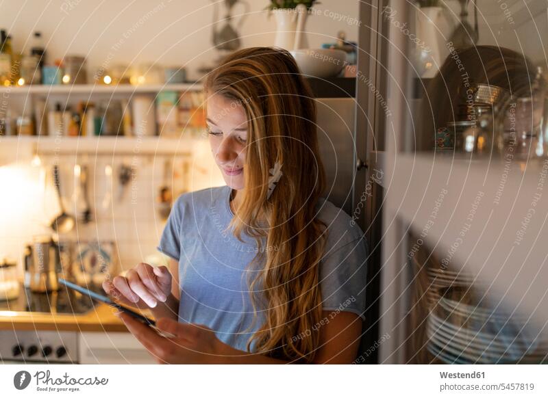 Young woman in kitchen at home using tablet human human being human beings humans person persons celibate celibates singles solitary people solitary person
