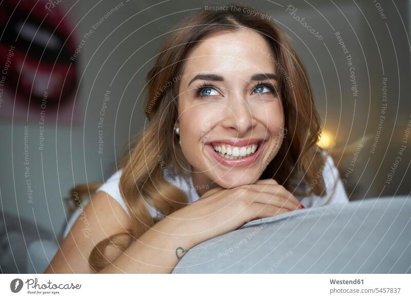 Portrait of happy young woman on couch settee sofa sofas couches settees smiling smile females women happiness laughing Laughter Adults grown-ups grownups adult