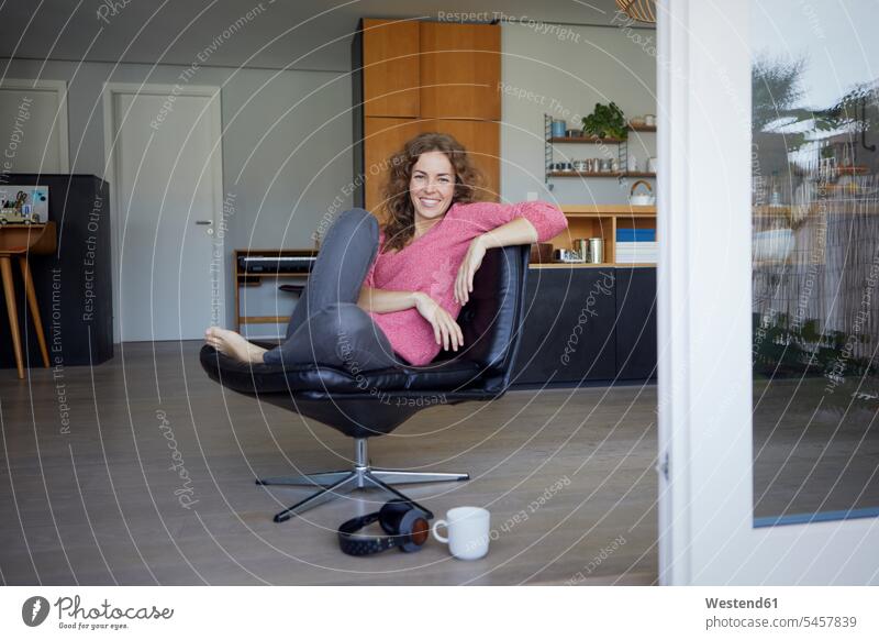 Smiling woman sitting on chair at home color image colour image day daylight shot daylight shots day shots daytime Home Interior Home Interiors domestic space