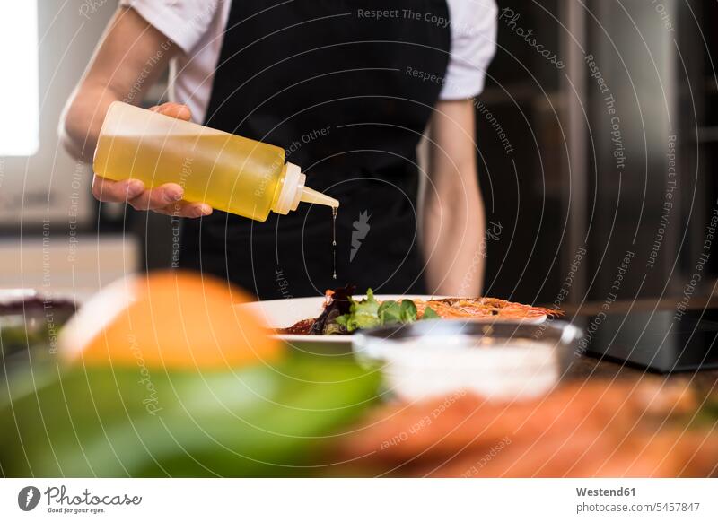 Close-up of woman cooking in kitchen pouring olive oil on a dish Spain preparing Food Preparation preparing food Selective focus Differential Focus flat flats