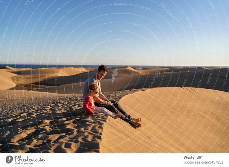 Father and daughter sitting on sand dune, Gran Canaria, Spain touristic tourists Eye Glasses Eyeglasses specs spectacles Pair Of Sunglasses sun glasses relax
