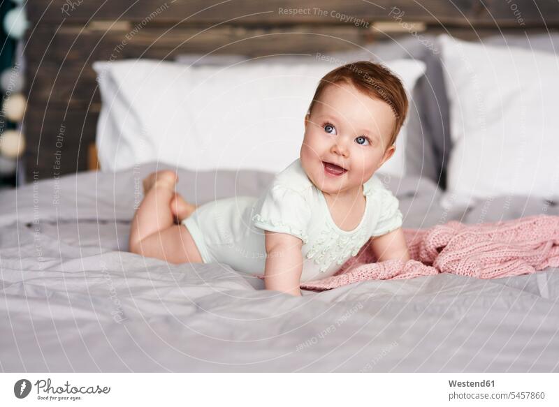 Happy baby lying on bed at home beds happiness happy infants nurselings babies laying down lie lying down people persons human being humans human beings